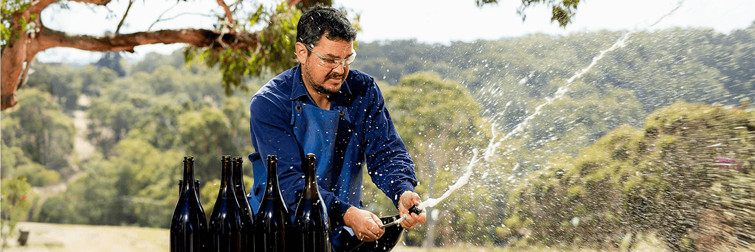 Dr. Martin Moran opening sparkling wine outdoors