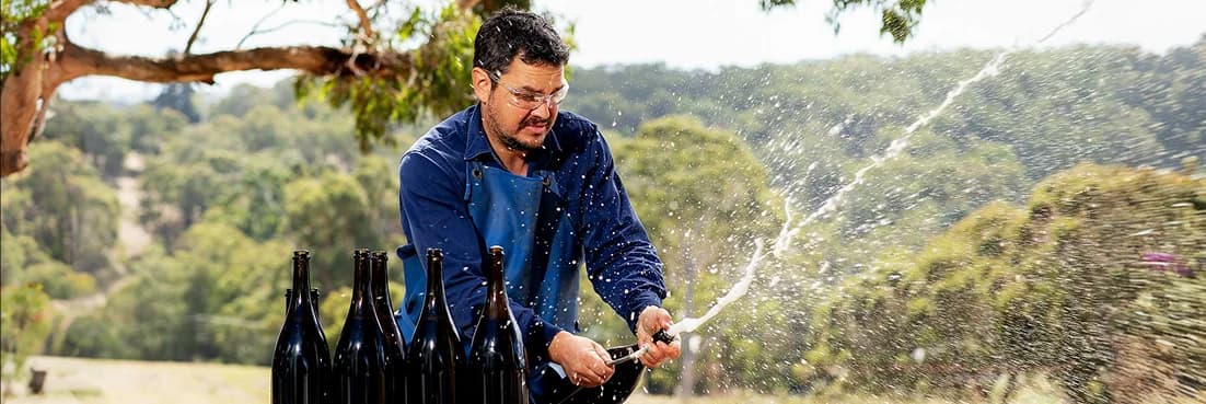 Dr. Martin Moran opening sparkling wine outdoors